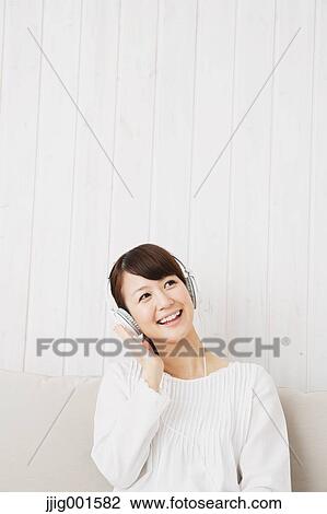 Japanese young woman in a white shirt with earphones on the sofa View Large Photo Image Stock Image - Japanese young woman in a white shirt with earphones on the sofa. Fotosearch