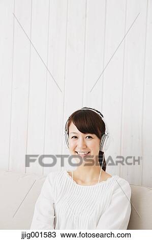 Japanese young woman in a white shirt with earphones on the sofa View Large Photo Image Stock Image - Japanese young woman in a white shirt with earphones on the sofa. Fotosearch
