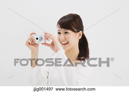 Japanese young woman in a white shirt with digital camera against white background View Large Photo Image Stock Photo - Japanese young woman in a white shirt with digital camera against white background. Fotosearch