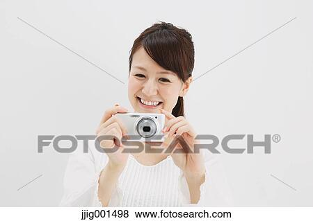 Japanese young woman in a white shirt with digital camera against white background View Large Photo Image Stock Photo - Japanese young woman in a white shirt with digital camera against white background. Fotosearch
