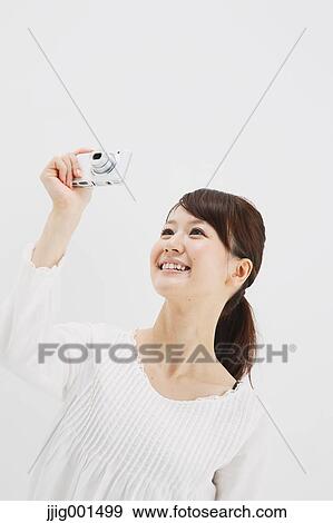 Japanese young woman in a white shirt with digital camera against white background View Large Photo Image Stock Photo - Japanese young woman in a white shirt with digital camera against white background. Fotosearch