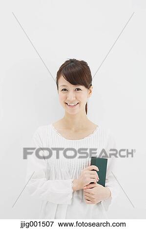 Japanese young woman in a white shirt with a book against white background View Large Photo Image Stock Photo - Japanese young woman in a white shirt with a book against white background. Fotosearch