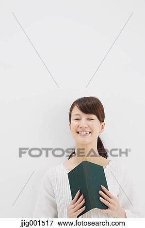 Japanese young woman in a white shirt with a book against white background View Large Photo Image Stock Photo - Japanese young woman in a white shirt with a book against white background. Fotosearch