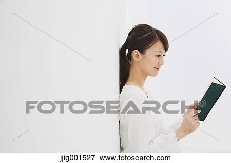 Stock Photo - Japanese young woman in a white shirt with a book against white background. Fotosearch