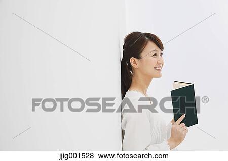 Japanese young woman in a white shirt with a book against white background View Large Photo Image Stock Photo - Japanese young woman in a white shirt with a book against white background. Fotosearch