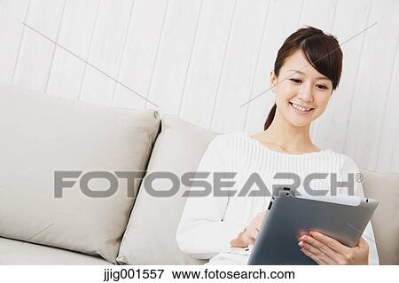 Japanese young woman in a white shirt with tablet on the sofa View Large Photo Image Stock Photo - Japanese young woman in a white shirt with tablet on the sofa. Fotosearch