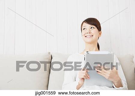 Japanese young woman in a white shirt with tablet on the sofa View Large Photo Image Stock Photo - Japanese young woman in a white shirt with tablet on the sofa. Fotosearch