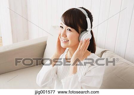 Japanese young woman in a white shirt with earphones on the sofa View Large Photo Image Stock Photo - Japanese young woman in a white shirt with earphones on the sofa. Fotosearch