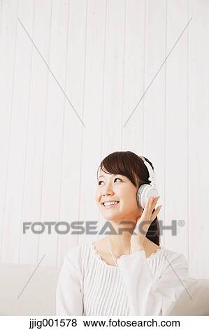 Japanese young woman in a white shirt with earphones on the sofa View Large Photo Image Stock Photo - Japanese young woman in a white shirt with earphones on the sofa. Fotosearch