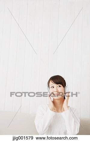 Japanese young woman in a white shirt with earphones on the sofa View Large Photo Image Stock Photo - Japanese young woman in a white shirt with earphones on the sofa. Fotosearch