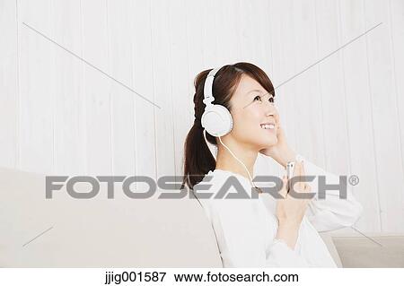 Japanese young woman in a white shirt with earphones on the sofa View Large Photo Image Stock Photo - Japanese young woman in a white shirt with earphones on the sofa. Fotosearch