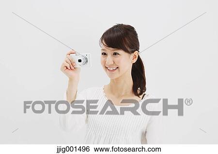 Japanese young woman in a white shirt with digital camera against white background View Large Photo Image Stock Photograph - Japanese young woman in a white shirt with digital camera against white background. Fotosearch