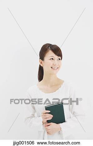 Stock Photograph - Japanese young woman in a white shirt with a book against white background. Fotosearch