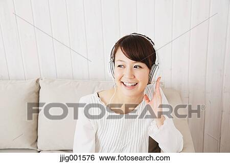 Japanese young woman in a white shirt with earphones on the sofa View Large Photo Image Stock Photograph - Japanese young woman in a white shirt with earphones on the sofa. Fotosearch