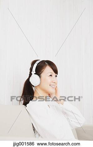Japanese young woman in a white shirt with earphones on the sofa View Large Photo Image Stock Photograph - Japanese young woman in a white shirt with earphones on the sofa. Fotosearch