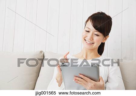 Japanese young woman in a white shirt with tablet on the sofa View Large Photo Image Stock Photography - Japanese young woman in a white shirt with tablet on the sofa. Fotosearch