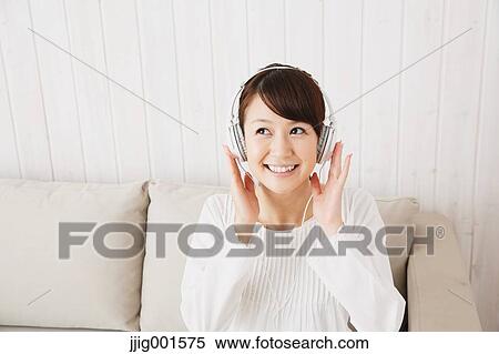 Japanese young woman in a white shirt with earphones on the sofa View Large Photo Image Stock Photography - Japanese young woman in a white shirt with earphones on the sofa. Fotosearch
