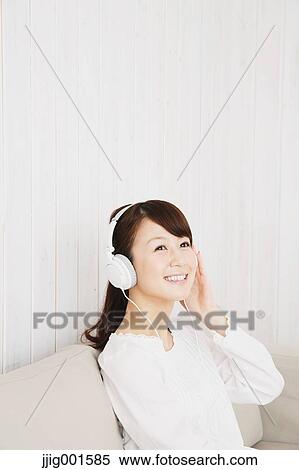 Japanese young woman in a white shirt with earphones on the sofa View Large Photo Image Stock Photography - Japanese young woman in a white shirt with earphones on the sofa. Fotosearch
