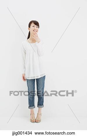 Japanese young woman in jeans and white shirt standing against white background View Large Photo Image Picture - Japanese young woman in jeans and white shirt standing against white background. Fotosearch