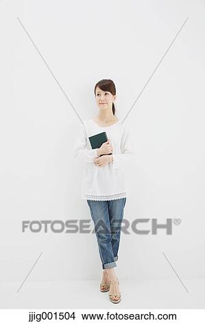 Japanese young woman in jeans and white shirt with a book against white background View Large Photo Image Picture - Japanese young woman in jeans and white shirt with a book against white background. Fotosearch