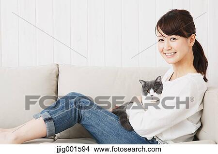 Japanese young woman in jeans and white shirt with cat on the sofa View Large Photo Image Picture - Japanese young woman in jeans and white shirt with cat on the sofa. Fotosearch