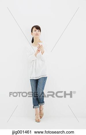 Japanese young woman in jeans and white shirt with smartphone standing against white background View Large Photo Image Stock Image - Japanese young woman in jeans and white shirt with smartphone standing against white background. Fotosearch