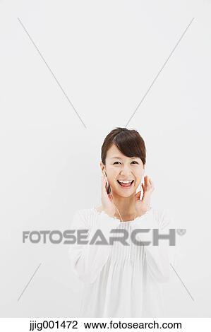 Japanese young woman in jeans and white shirt with earphones standing against white background View Large Photo Image Stock Image - Japanese young woman in jeans and white shirt with earphones standing against white background. Fotosearch