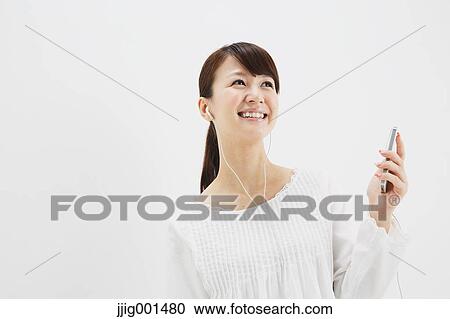 Japanese young woman in jeans and white shirt with earphones standing against white background View Large Photo Image Stock Image - Japanese young woman in jeans and white shirt with earphones standing against white background. Fotosearch