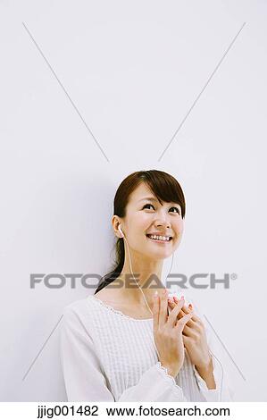 Japanese young woman in jeans and white shirt with earphones standing against white background View Large Photo Image Stock Image - Japanese young woman in jeans and white shirt with earphones standing against white background. Fotosearch