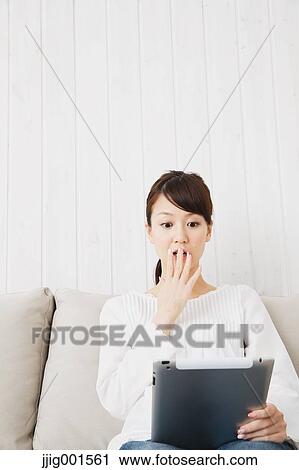 Japanese young woman in jeans and white shirt with tablet on the sofa View Large Photo Image Stock Image - Japanese young woman in jeans and white shirt with tablet on the sofa. Fotosearch