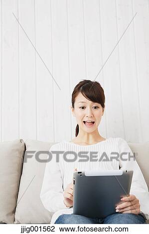 Japanese young woman in jeans and white shirt with tablet on the sofa View Large Photo Image Stock Image - Japanese young woman in jeans and white shirt with tablet on the sofa. Fotosearch