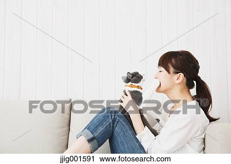 Japanese young woman in jeans and white shirt with cat on the sofa View Large Photo Image Stock Image - Japanese young woman in jeans and white shirt with cat on the sofa. Fotosearch
