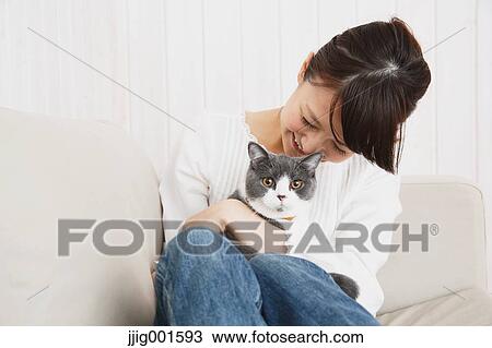 Japanese young woman in jeans and white shirt with cat on the sofa View Large Photo Image Stock Image - Japanese young woman in jeans and white shirt with cat on the sofa. Fotosearch