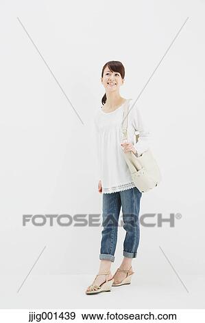 Japanese young woman in jeans and white shirt standing against white background View Large Photo Image Stock Photo - Japanese young woman in jeans and white shirt standing against white background. Fotosearch