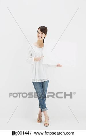 Japanese young woman in jeans and white shirt standing against white background View Large Photo Image Stock Photo - Japanese young woman in jeans and white shirt standing against white background. Fotosearch