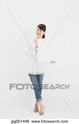 Stock Photo - Japanese young woman in jeans and white shirt standing against white background. Fotosearch