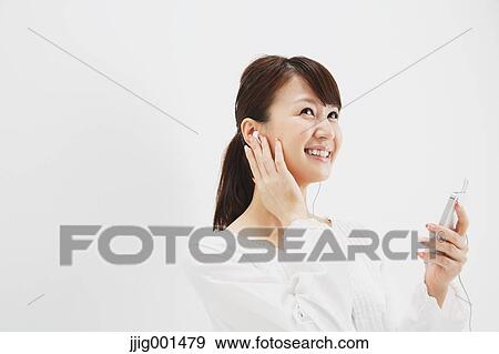 Japanese young woman in jeans and white shirt with earphones standing against white background View Large Photo Image Stock Photo - Japanese young woman in jeans and white shirt with earphones standing against white background. Fotosearch