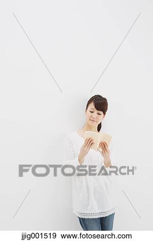 Japanese young woman in jeans and white shirt with a book against white background View Large Photo Image Stock Photo - Japanese young woman in jeans and white shirt with a book against white background. Fotosearch