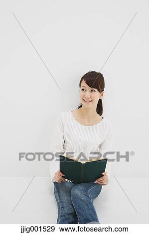 Japanese young woman in jeans and white shirt with a book against white background View Large Photo Image Stock Photo - Japanese young woman in jeans and white shirt with a book against white background. Fotosearch
