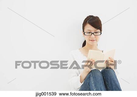 Stock Photo - Japanese young woman in jeans and white shirt with a book against white background. Fotosearch