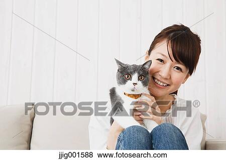 Japanese young woman in jeans and white shirt with cat on the sofa View Large Photo Image Stock Photo - Japanese young woman in jeans and white shirt with cat on the sofa. Fotosearch
