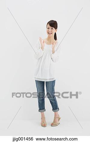 Stock Photograph - Japanese young woman in jeans and white shirt standing against white background. Fotosearch