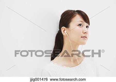 Japanese young woman in jeans and white shirt with earphones standing against white background View Large Photo Image Stock Photograph - Japanese young woman in jeans and white shirt with earphones standing against white background. Fotosearch