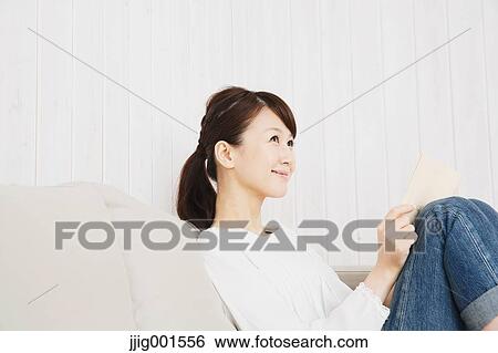 Japanese young woman in jeans and white shirt with a book on the sofa View Large Photo Image Stock Photograph - Japanese young woman in jeans and white shirt with a book on the sofa. Fotosearch