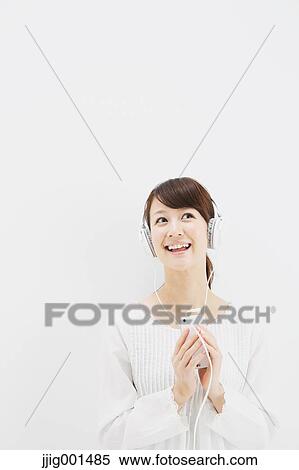 Japanese young woman in jeans and white shirt with earphones standing against white background View Large Photo Image Stock Photography - Japanese young woman in jeans and white shirt with earphones standing against white background. Fotosearch