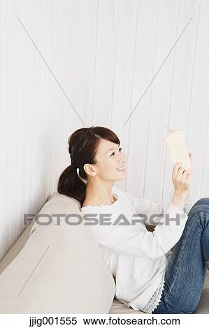 Japanese young woman in jeans and white shirt with a book on the sofa View Large Photo Image Stock Photography - Japanese young woman in jeans and white shirt with a book on the sofa. Fotosearch