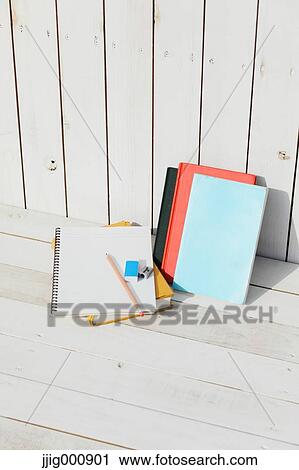 Stock Image - Pencil and notebooks against white wooden wall. Fotosearch