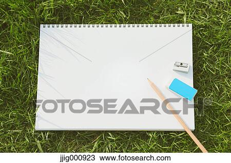 Stock Image - Pencil and sketchbook on grass. Fotosearch
