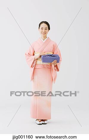 Stock Image - Young Japanese woman in a traditional kimono against white background. Fotosearch