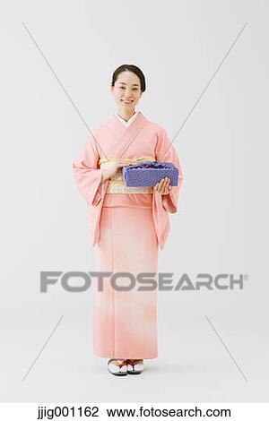 Stock Image - Young Japanese woman in a traditional kimono against white background. Fotosearch